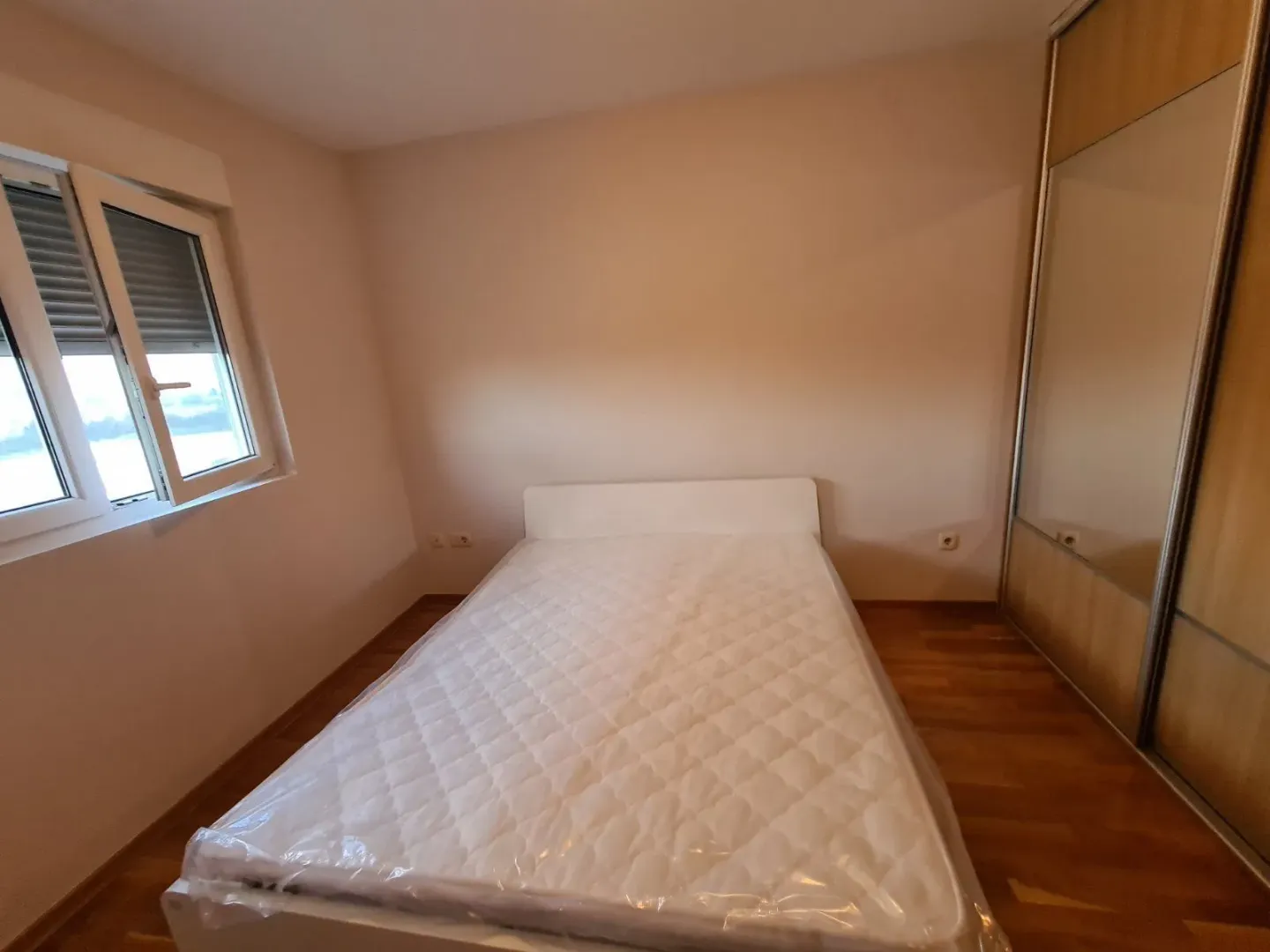 Svijetla spavaća soba sa krevetom i ormarom.