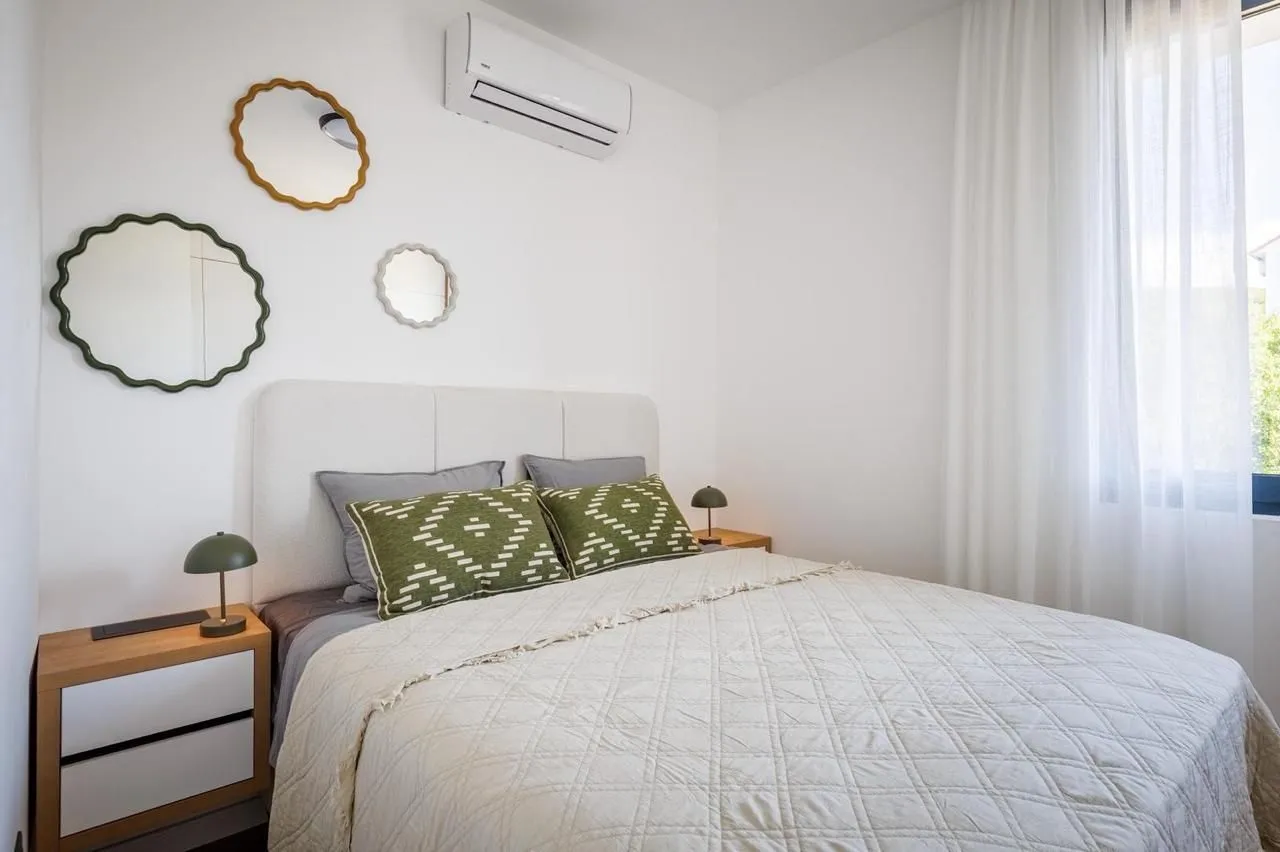 Furnished bedroom with a double bed, bedside tables, and decorative mirrors on the wall.