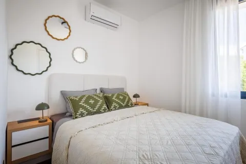 Furnished bedroom with a double bed, bedside tables, and decorative mirrors on the wall. - image 18