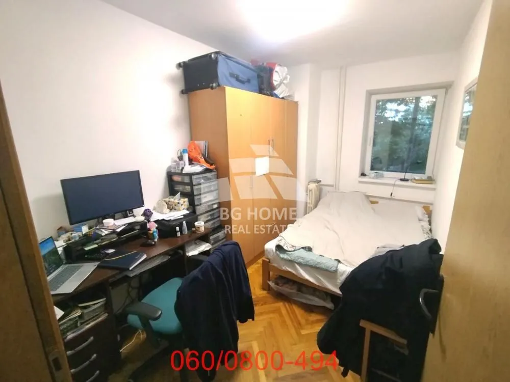 Nameštena spavaća soba sa krevetom, radnim stolom i ormarom.