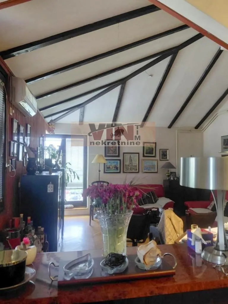 Living room with a sloping ceiling and wooden beams.