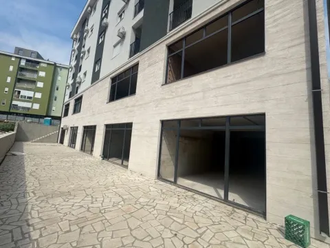 Exterior view of the building with ground floor commercial space and a paved courtyard. - image 2