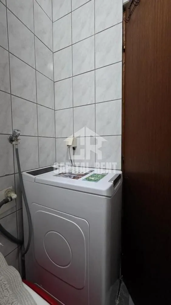 Kupatilo sa belom veš mašinom i pločicama na zidovima.