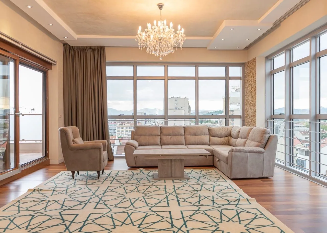 Spacious and bright living room with a sofa, rug, and large windows.
