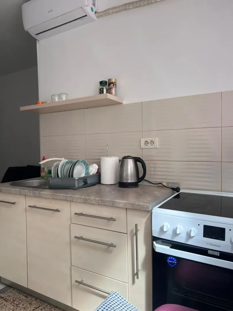Manja kuhinja sa elementima, šporetom i radnom površinom.
