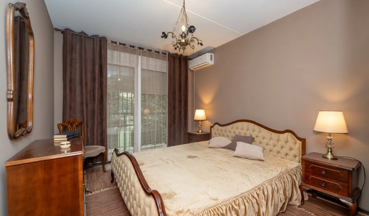Furnished bedroom with a double bed, bedside tables, and a dresser.