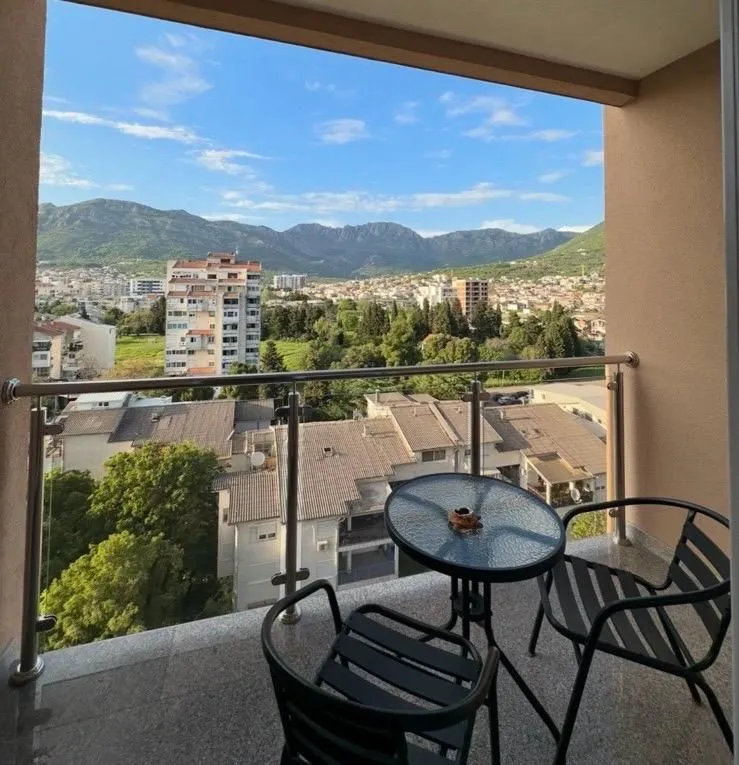 Furnished balcony with seating set and a view of the city and mountains.