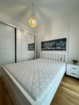 Svjetla i uredna spavaća soba sa bijelim krevetom, velikim garderoberom i noćnim stočićem. - image 7
