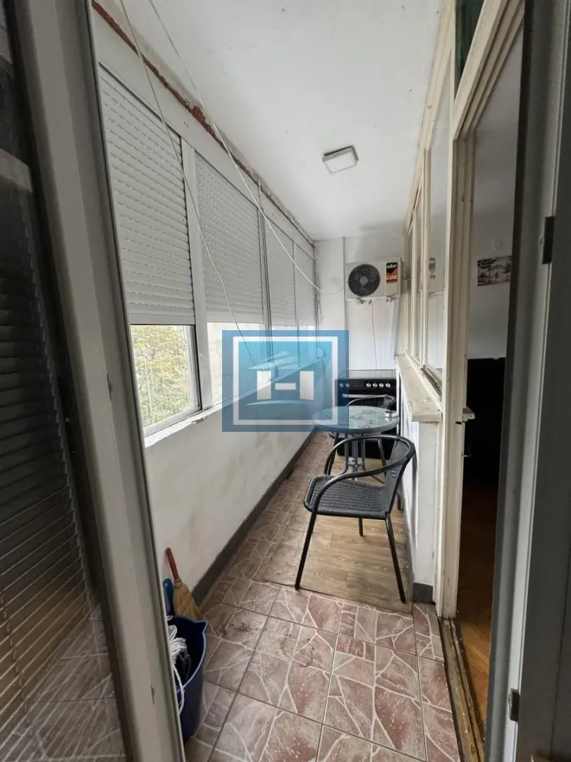 Enclosed balcony with a table, chairs, and air conditioning unit.