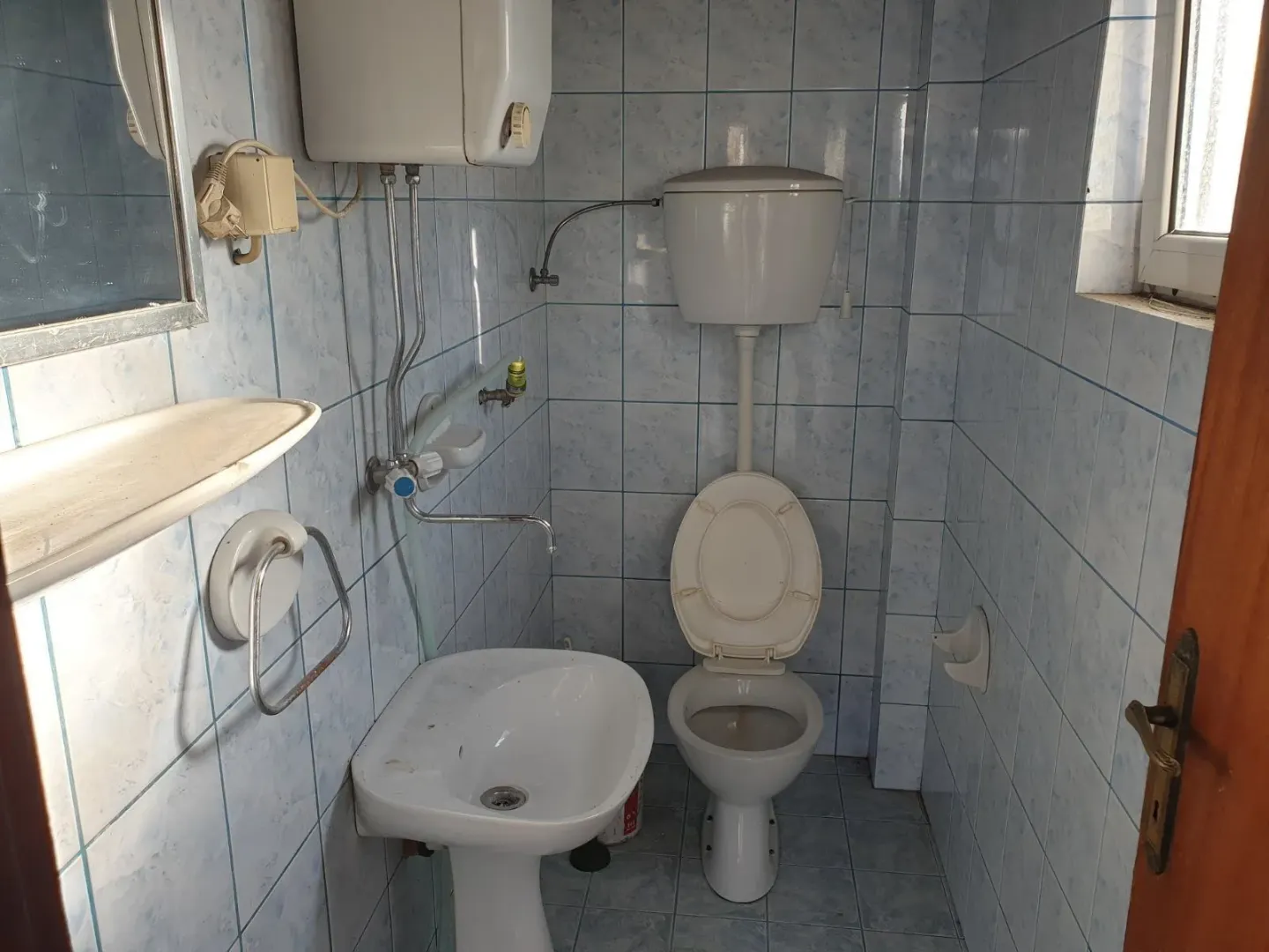 A simple bathroom with blue tiles, a sink, and a toilet.
