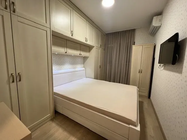 Svijetla spavaća soba sa velikim bračnim krevetom i ugradnim plakarima.