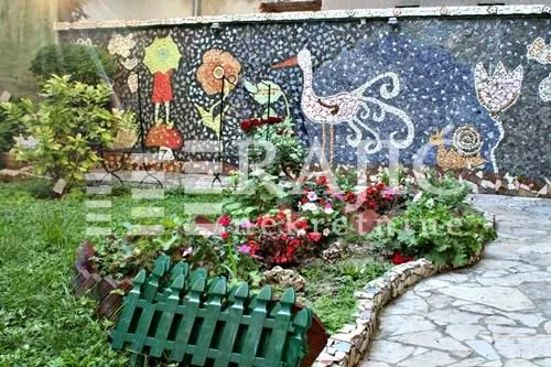 Landscaped courtyard with a wall mosaic and flower beds.
