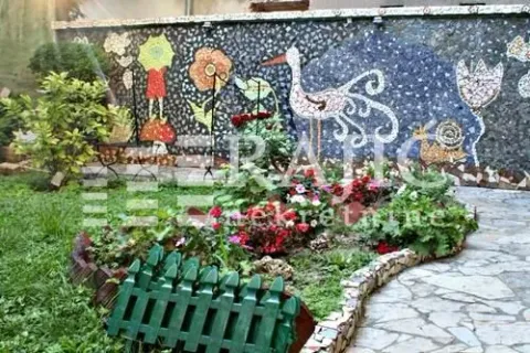 Landscaped courtyard with a wall mosaic and flower beds. - image 14