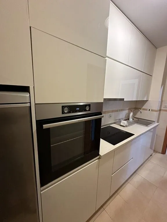 Moderna kuhinja sa ugrađenom rernom, ravnom pločom i gornjim elementima.