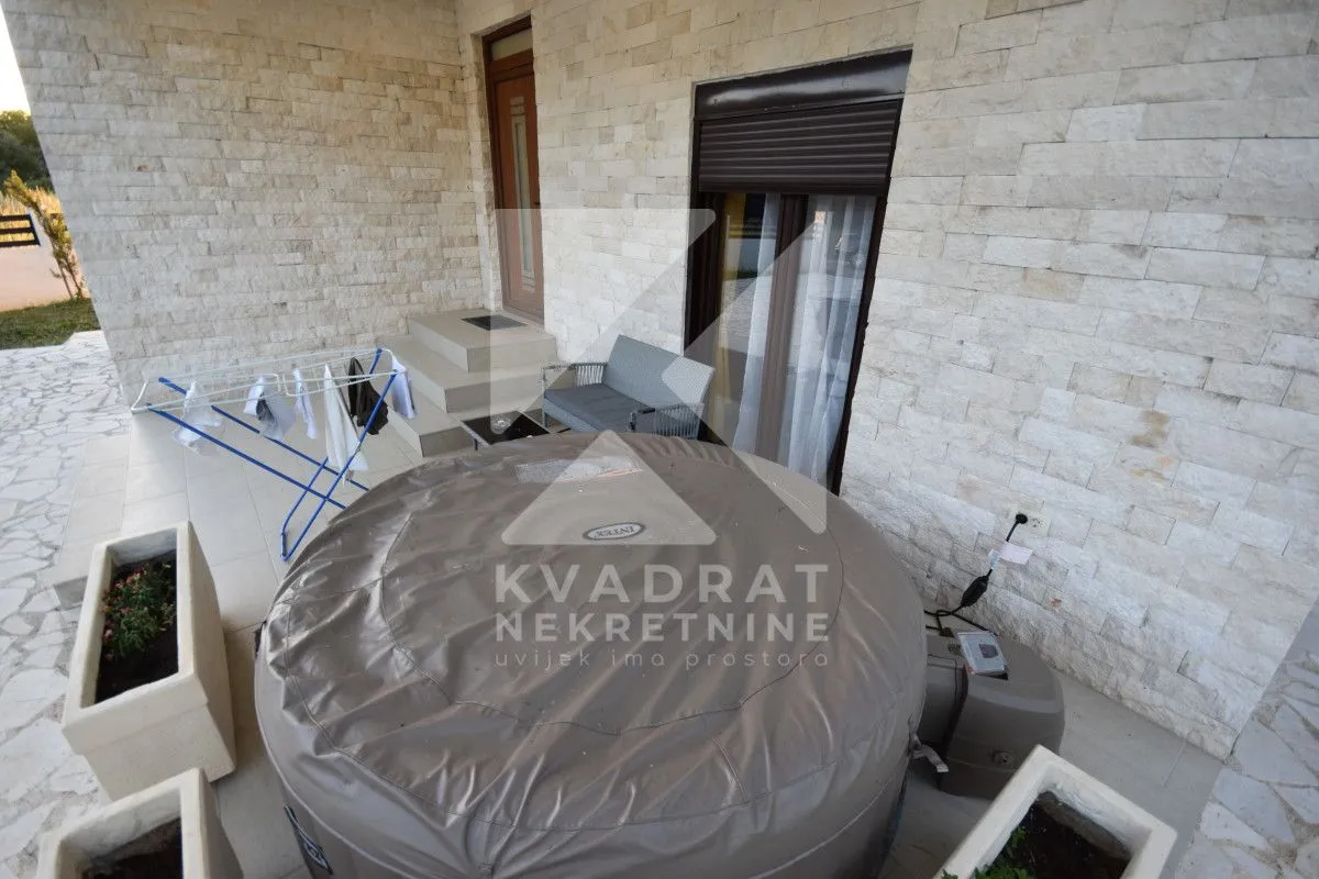 Terrace with a hot tub, seating set, and stone facade.