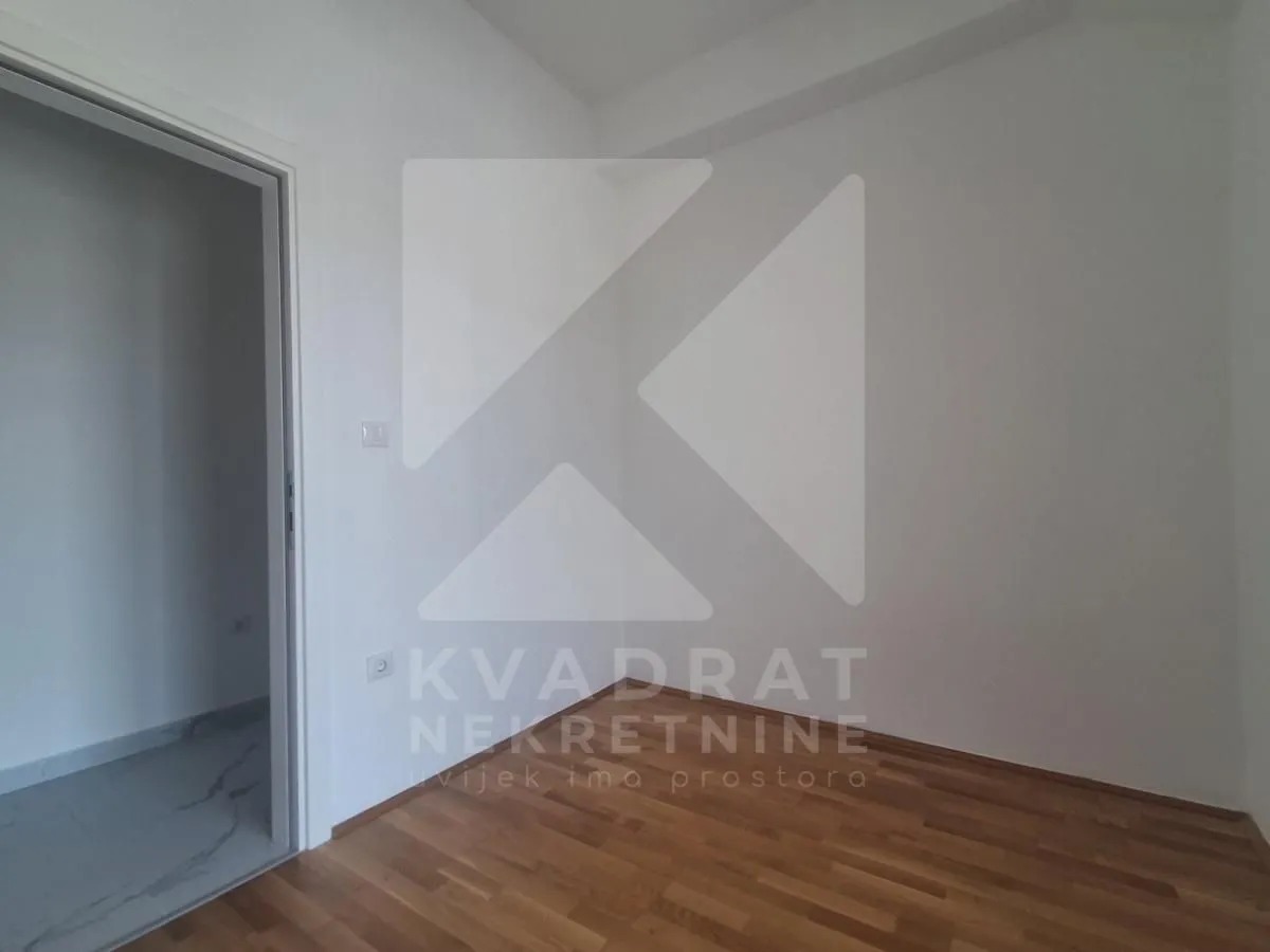 Empty room with hardwood flooring and white walls.