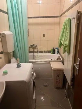 Manje kupatilo sa kadom, veš mašinom i pločicama na zidovima. - image 8