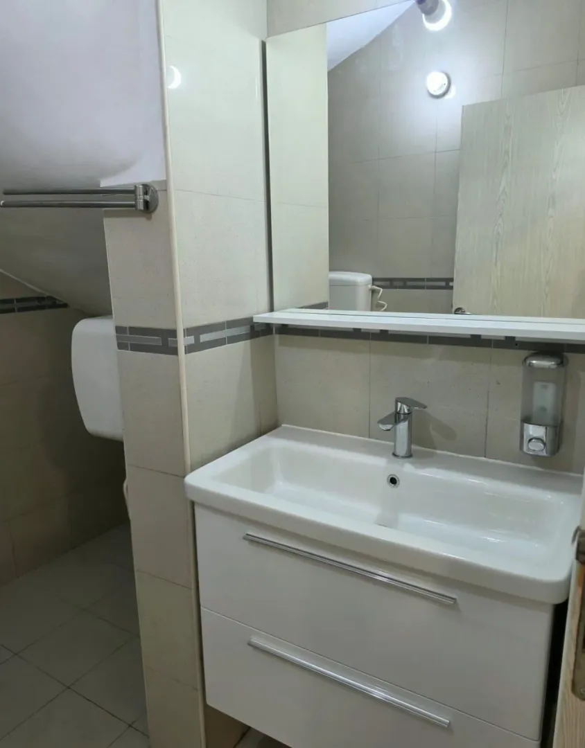 Smaller bathroom with a washbasin, mirror and neutral-toned tiles.