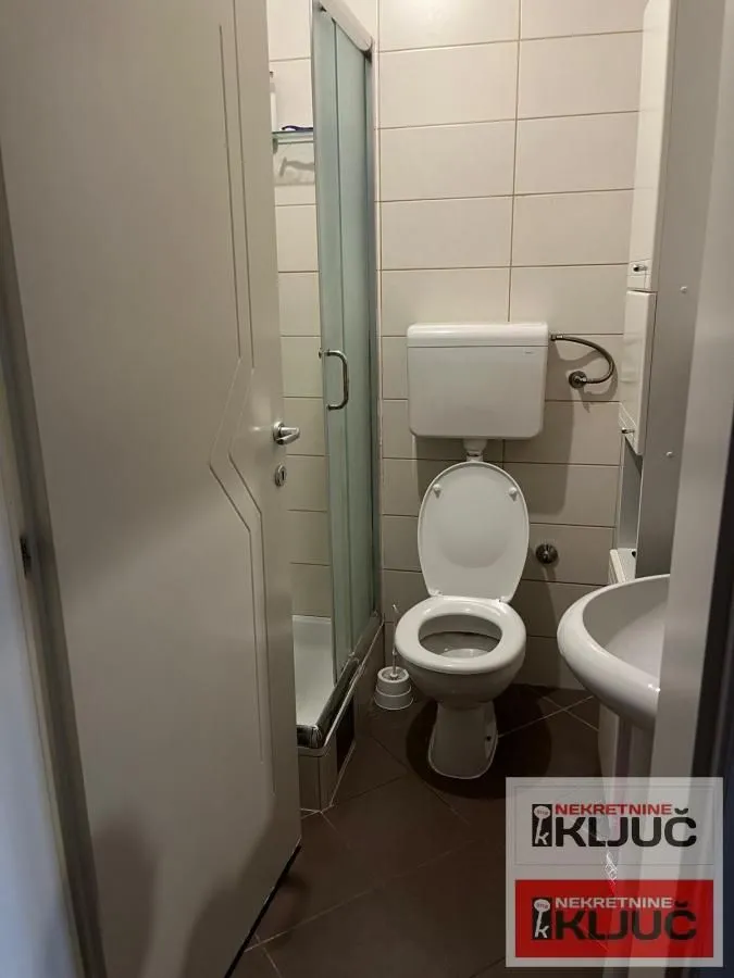 Small bathroom with a shower cabin, toilet, and sink.