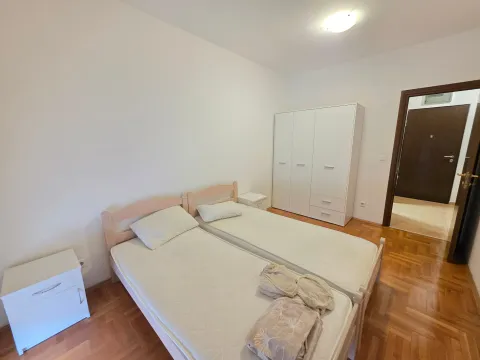 Bedroom with two single beds, a white wardrobe, and parquet flooring. - image 6