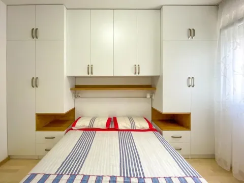 Double bed surrounded by white built-in closets and shelves. - image 2