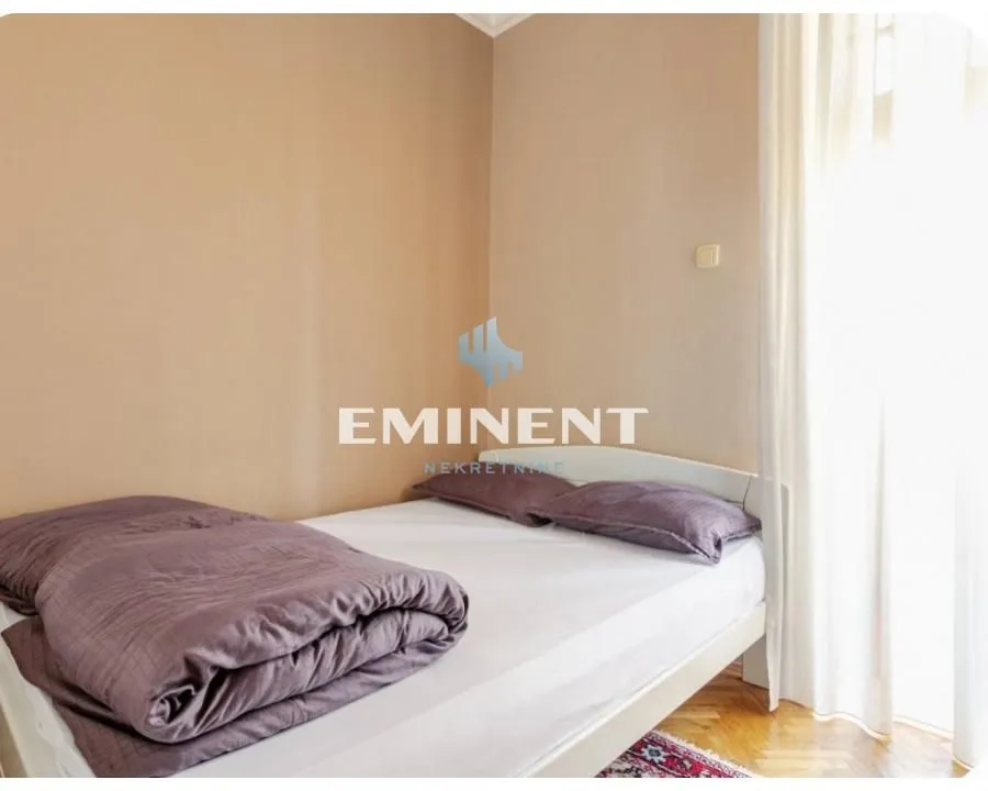 Small bedroom with a double bed and a window with a white curtain.