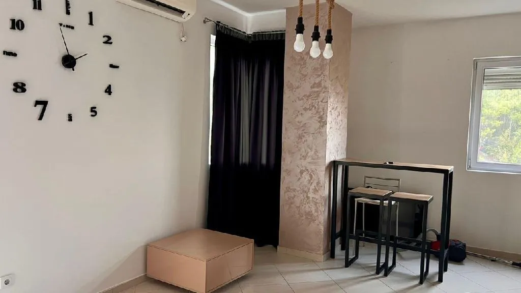 Living room with a modern wall clock and a dining table with chairs.