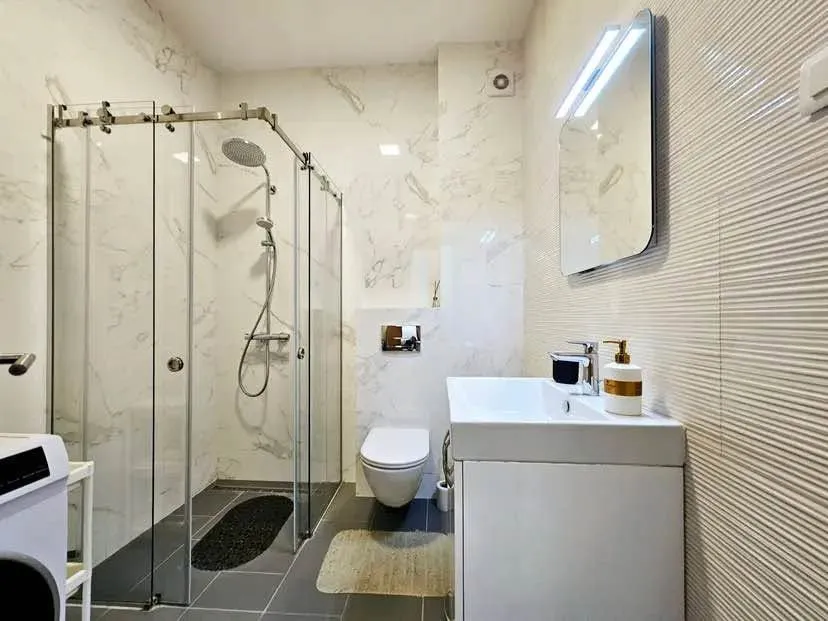 Moderno opremljeno kupatilo sa tuš kabinom, umivaonikom i toaletom.