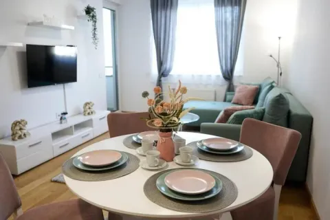 Trpezarijski sto sa stolicama i pogledom na dnevni boravak sa garniturom i televizorom. - image 3