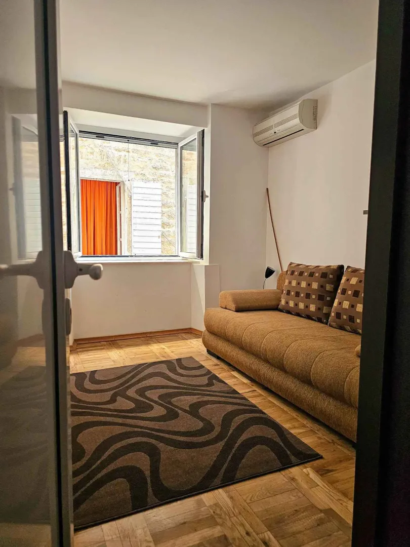 Small living room with a sofa and a window overlooking the neighboring building.