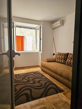 Small living room with a sofa and a window overlooking the neighboring building. - image 6
