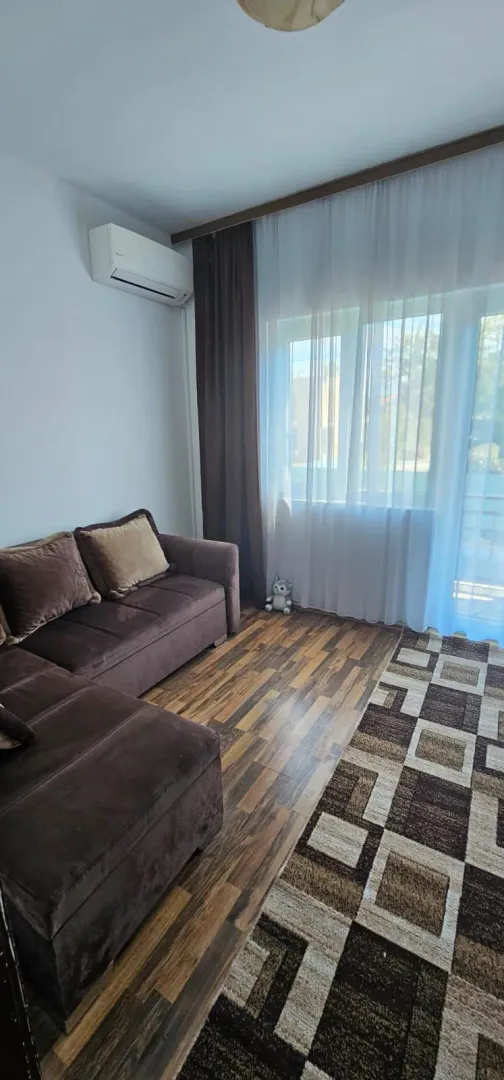 Living room with a corner sofa, air conditioning and a large window with curtains.
