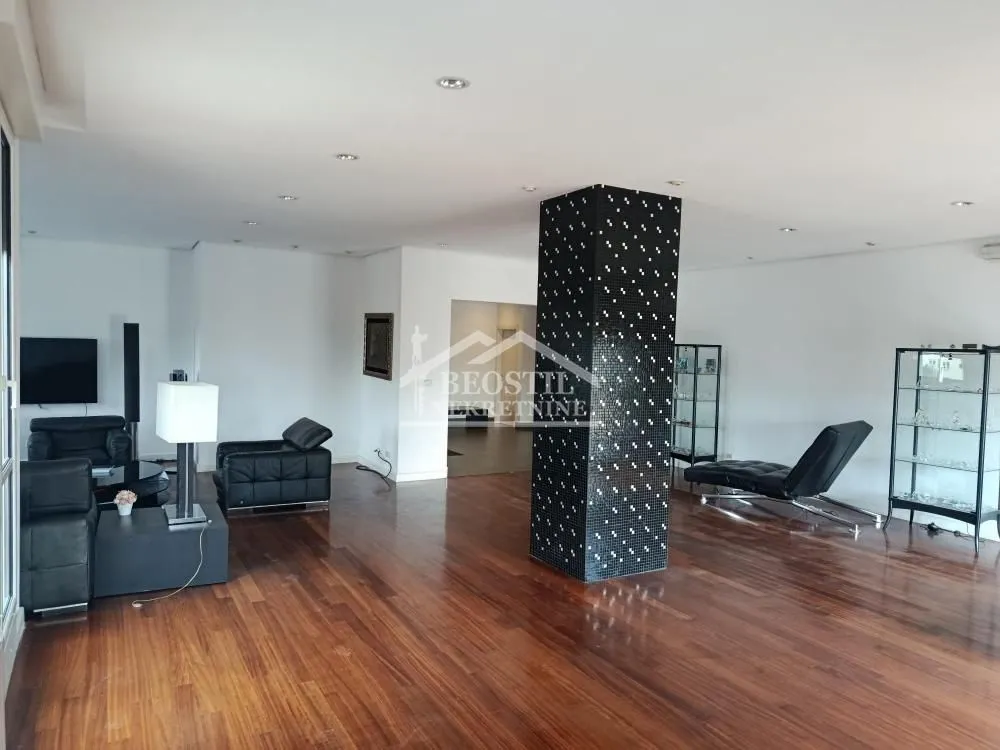 Spacious living room with wooden flooring and a central mosaic-tiled pillar.