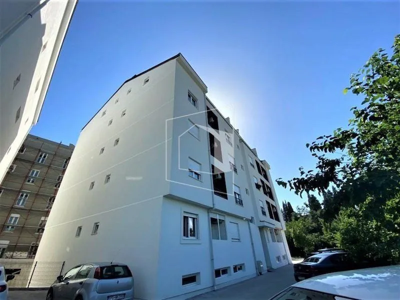 Spoljašnji izgled stambene zgrade sa svijetlom fasadom.