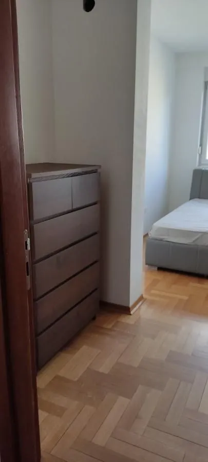 Pogled iz hodnika na spavaću sobu sa krevetom i komodom.