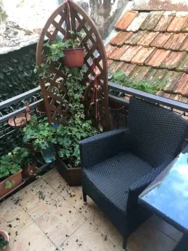 Manji balkon sa drvenom pregradom za biljke i crnom pletenom foteljom. - image 17