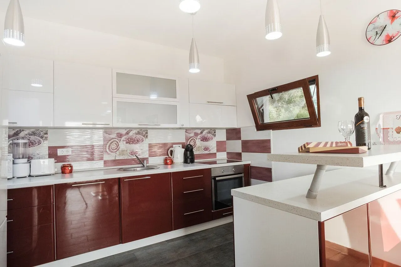 Modern kitchen with white and dark red cabinets, a breakfast bar, and built-in appliances.