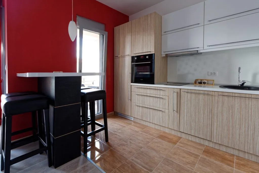 Modern kitchen with wooden cabinets, a breakfast bar, and access to the terrace.