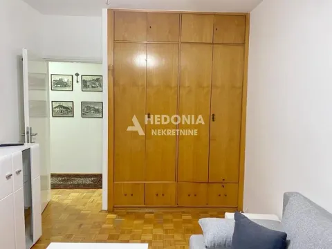 Spavaća soba sa velikim drvenim ormarom i parketom na podu. - image 14