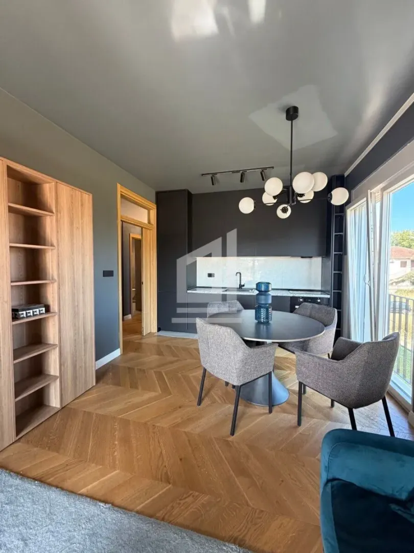 Dining area with a modern table and chairs, connected to the kitchen in the background.
