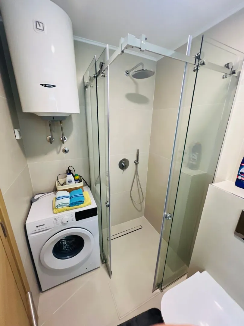 Compact bathroom with a shower cabin, washing machine, and water heater.