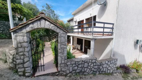 Dvorište sa kamenim ulaznim lukom i kapijom ispred kuće sa balkonom. - image 5