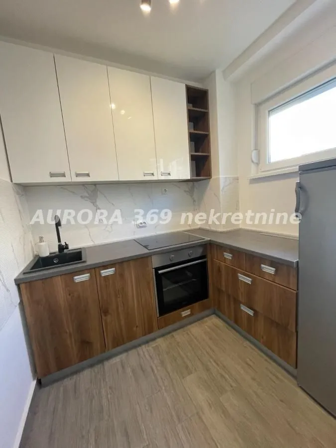 Smaller L-shaped kitchen with a built-in oven and wood-decor cabinets.