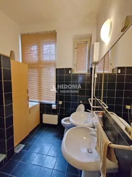 Kupatilo sa tamnim pločicama, dva umivaonika, wc šoljom i prozorom. - image 8