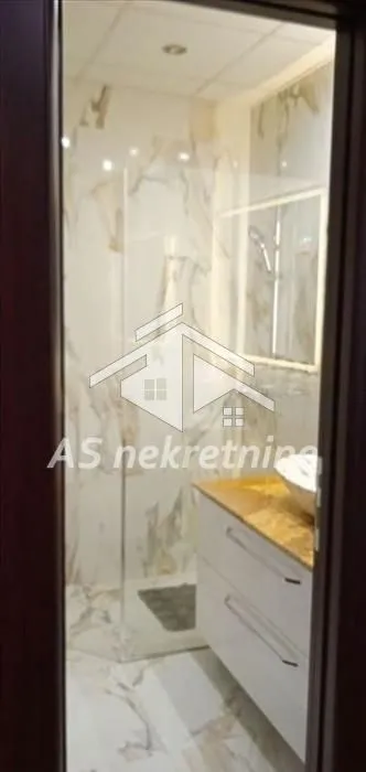 Pogled kroz vrata na moderno opremljeno kupatilo sa tuš kabinom.