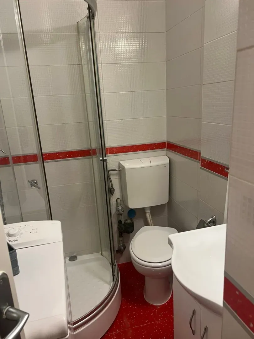 Bathroom equipped with a shower cabin, toilet, sink, and washing machine.