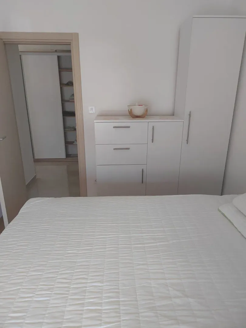 Namještena spavaća soba sa bračnim krevetom, garderoberom i komodom.
