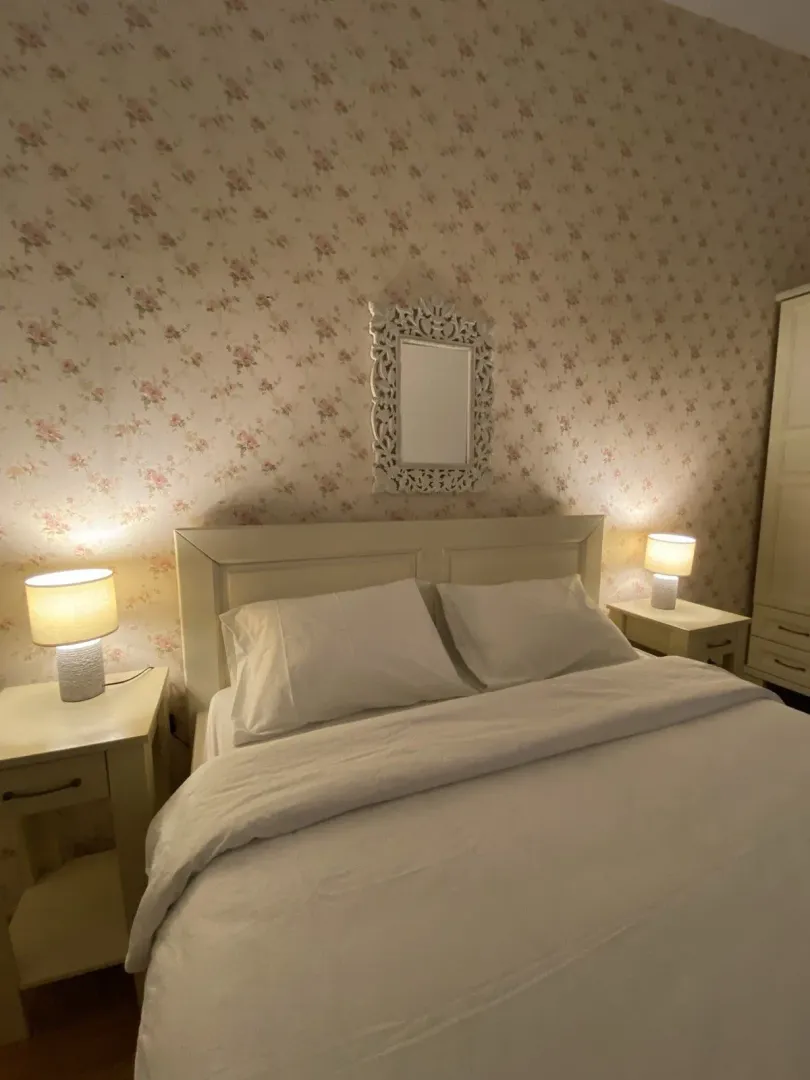Cozy bedroom featuring floral wallpaper and bedside lamps.