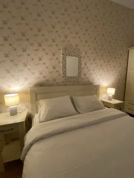 Cozy bedroom featuring floral wallpaper and bedside lamps. - image 9