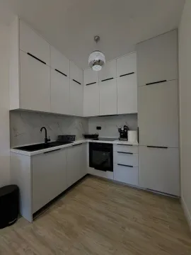 Modern white kitchen with built-in oven, sink, and cabinetry. - image 2